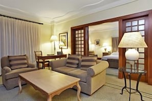 Une chambre d’hôtel comprenant un canapé, une table basse en bois, une lampe et un lit.