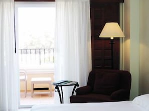 A hotel room with a bed, a chair, a table, and a lamp. There is a balcony with a chair and a table. - Grand Hyatt La Manga Club Golf & Spa (Murcia)