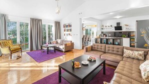A spacious living room with a sofa, a coffee table, and a bookshelf. - VILLA SEABIRD Holiday House with Private Pool (Nova Vas)