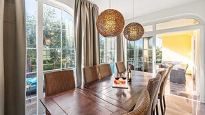 A dining area with a large wooden table, wicker chairs, and two spherical woven light fixtures. - VILLA SEABIRD Holiday House with Private Pool (Nova Vas)
