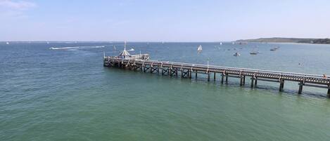 Eine Pier, die sich in ruhiges Wasser erstreckt, mit Booten und wolkenlosem Himmel.
