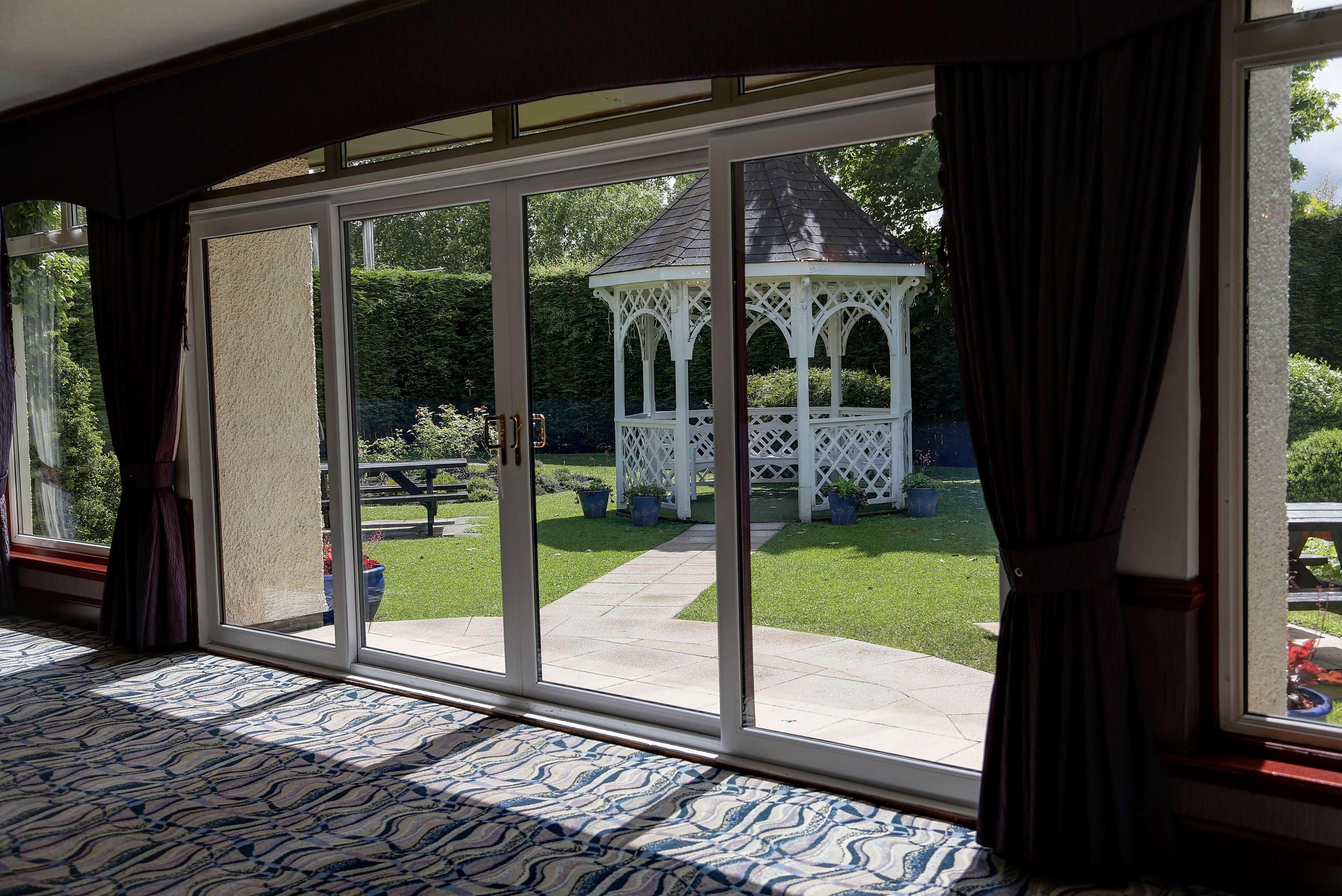A room with a large sliding glass door leading to a patio with a gazebo and a lawn.