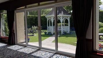 A room with a large sliding glass door leading to a patio with a gazebo and a lawn.