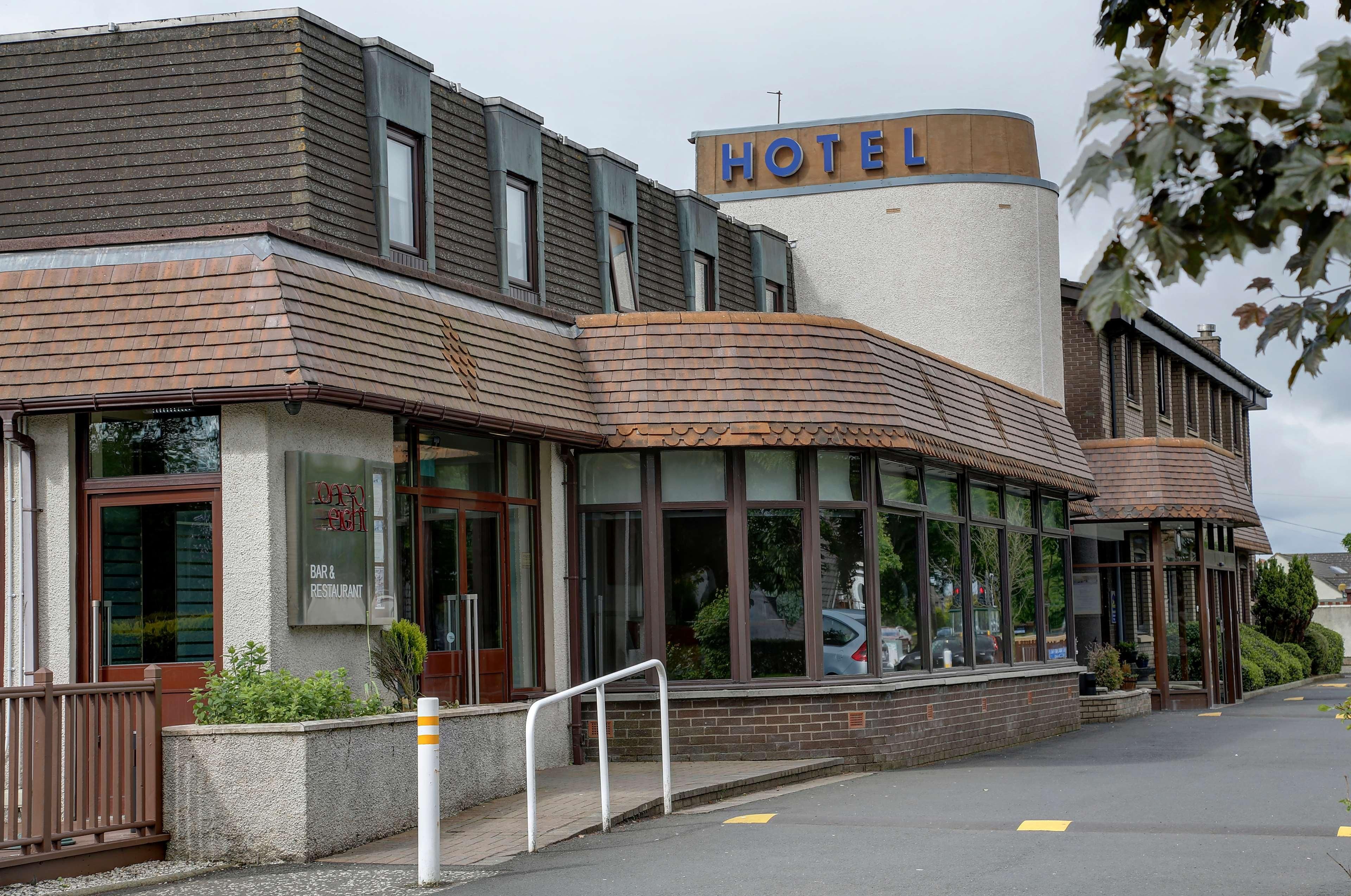 A hotel with a modern design, featuring a prominent 'HOTEL' sign, large windows, and a brick facade.