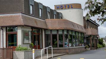 A hotel with a modern design, featuring a prominent 'HOTEL' sign, large windows, and a brick facade.