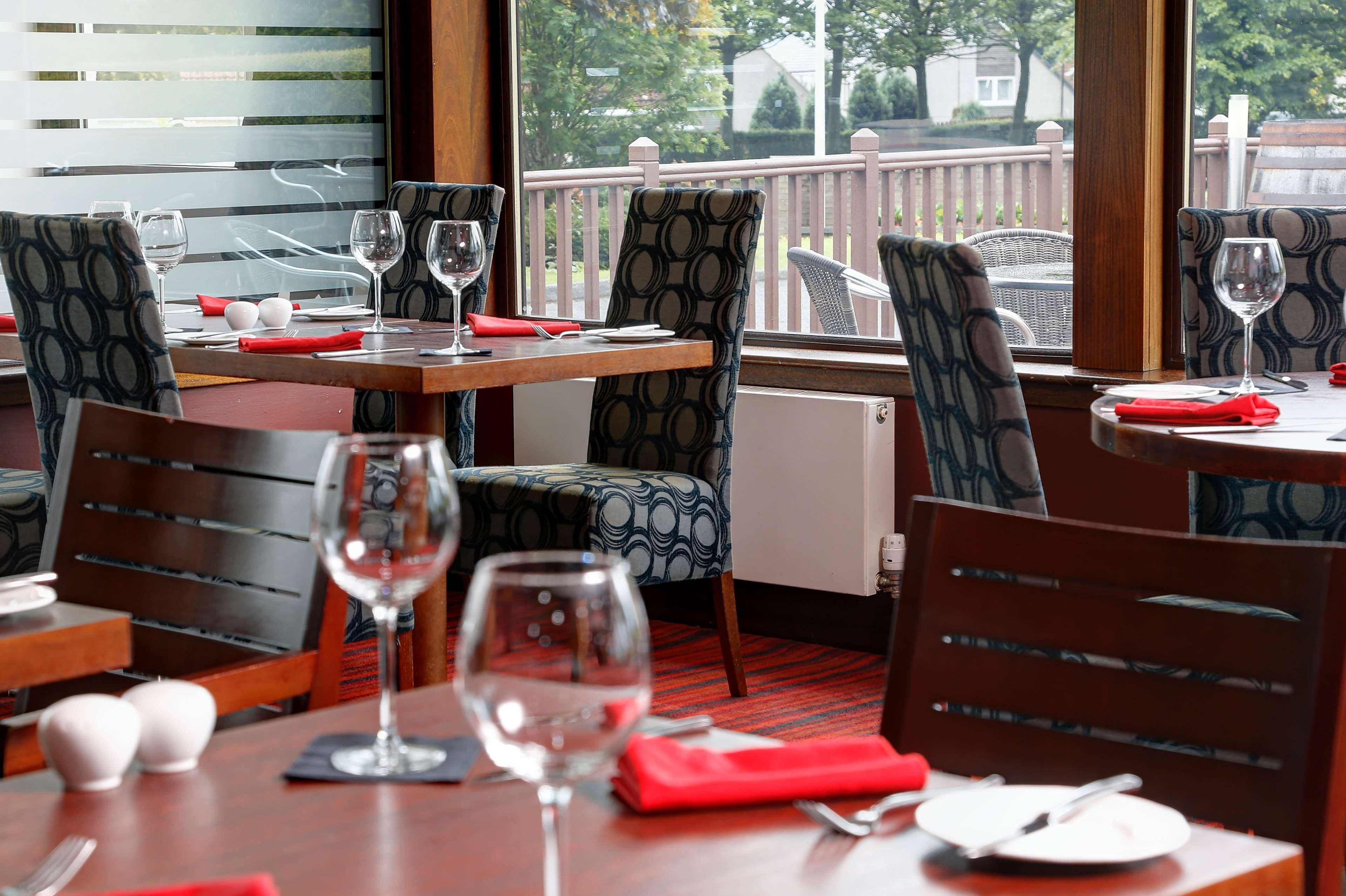 A restaurant with tables set for dining, chairs, and wine glasses.