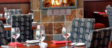 Un restaurante con mesas redondas, sillas y una chimenea.
