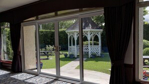A room with a large sliding glass door leading to a patio with a gazebo and a lawn. - Best Western Glasgow Livingston Hilcroft Hotel (Bathgate)