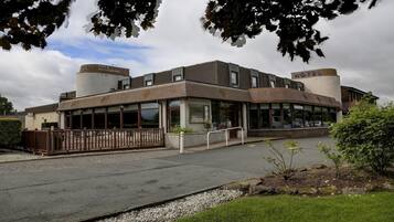 A hotel with a bar and restaurant, a parking lot, and a well-maintained lawn.