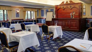 A conference room with tables, chairs, a whiteboard, and a wooden panel with decorative carvings.