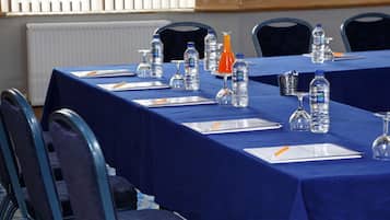 A conference table set with water bottles, glasses, and notepads, surrounded by chairs.