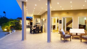 A spacious outdoor patio area with a dining table and chairs, a seating area with sofas, and a staircase leading to an upper level. - Central Villa, big spaces, 180° Seaview with infinite Pool con hot Jacuzzi (Las Terrenas)