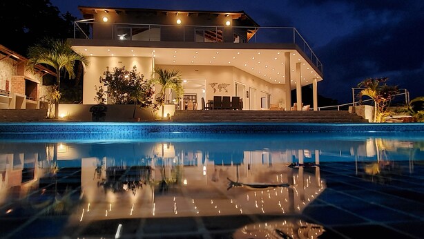 A modern house with a swimming pool, outdoor seating, and a well-lit patio area. - Central Villa, big spaces, 180° Seaview with infinite Pool con hot Jacuzzi (Las Terrenas)