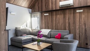 A modern living room with a grey sectional sofa, a wooden coffee table, and a red heart-shaped pillow.