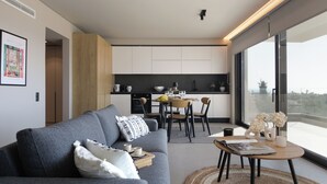 Una sala de estar moderna con un sofá gris, un comedor con una mesa y sillas, y una cocina al fondo.