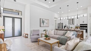 Ein modernes Wohnzimmer mit Sofa, Couchtisch und Essbereich, im Hintergrund ist eine Küche zu sehen.