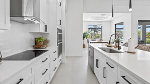 Eine moderne Küche mit weißen Schränken, einem schwarzen Kochfeld und einer großen Kochinsel mit Spüle.