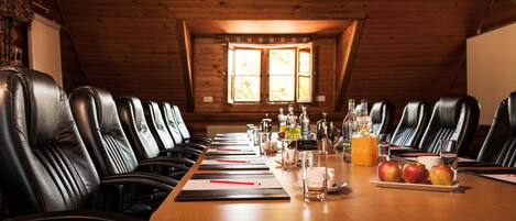 A conference room with leather chairs, a long table, and various items like bottles, glasses, and apples.