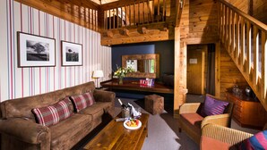 Un intérieur en bois avec un canapé en cuir marron, un fauteuil en osier et une table basse en bois.