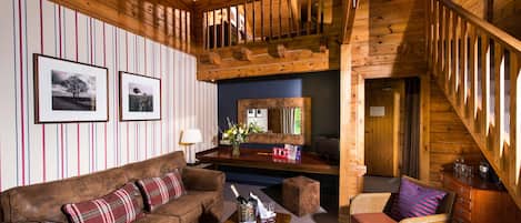 Un interior de madera con un sofá de cuero marrón, un sillón de mimbre y una mesa de centro de madera.