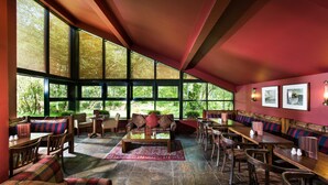Un vaste espace intérieur doté de grandes fenêtres, d’un mobilier confortable et d’un plafond rouge.