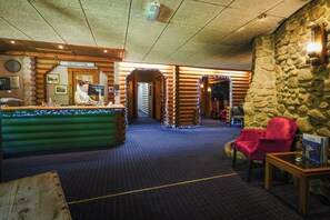 Un espace d’accueil avec un bureau en bois, une enseigne indiquant « réception » et un mur en pierre.