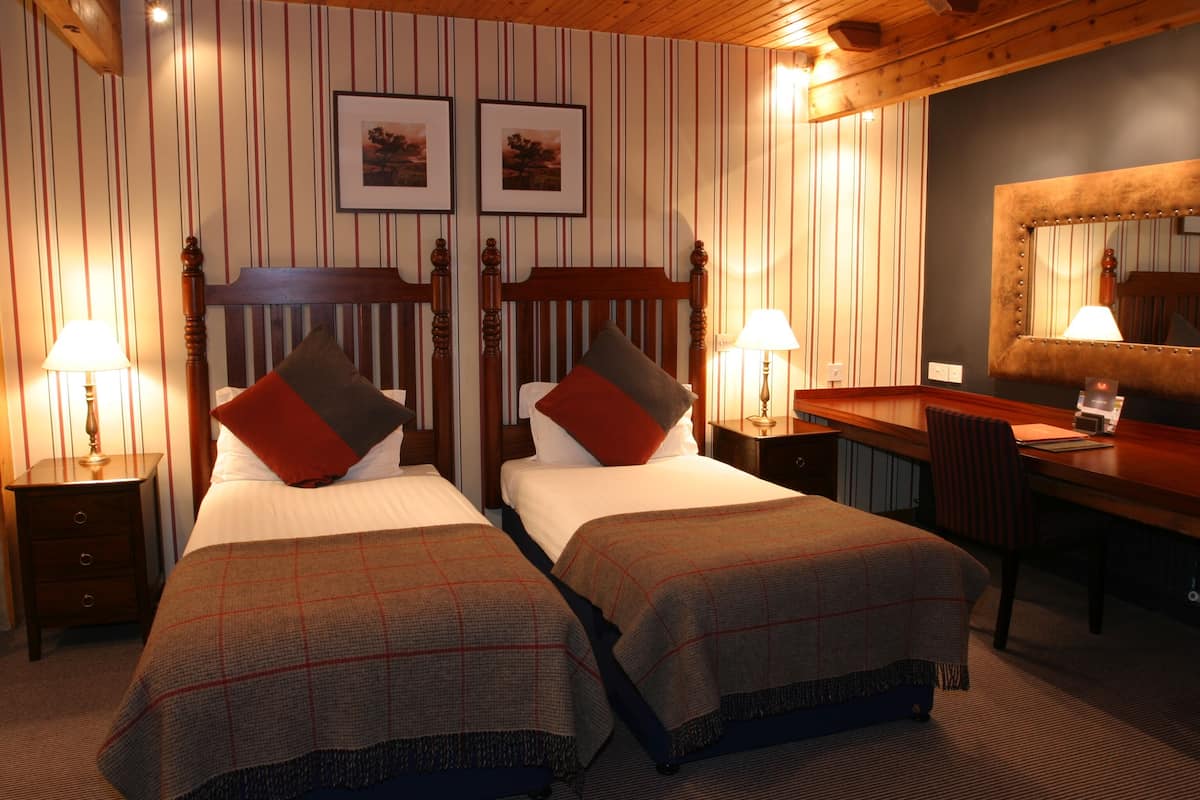 Ein Hotelzimmer mit zwei Betten, einem Schreibtisch und einem Spiegel.