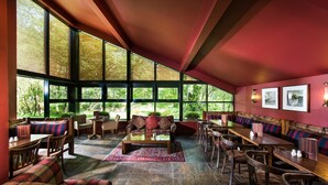 A spacious indoor area with large windows, seating arrangements, and a red ceiling.