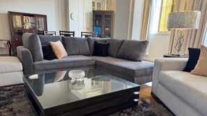 Ein modernes Wohnzimmer mit einer Eckcouch, einem Glastisch und einem Fellteppich.
