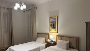 Ein Hotelzimmer mit zwei Einzelbetten, einem Nachttisch mit Lampe, einem Gemälde an der Wand und einem Holzschrank.
