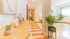A modern living room with a wooden coffee table, a stone pillar, and a view of the bathroom through an open door. - Your Ideal Base to explore Zaragoza`s delights (Zaragoza)