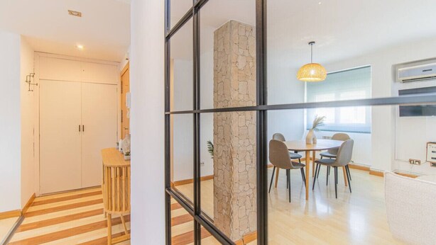 A modern kitchen with a stone accent wall, a dining area with a round table and chairs, and a staircase leading to another level. - Your Ideal Base to explore Zaragoza`s delights (Zaragoza)