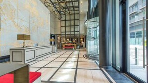 Un vestíbulo amplio con techo alto, un área de estar central y ventanas grandes que ofrecen vistas al exterior.
