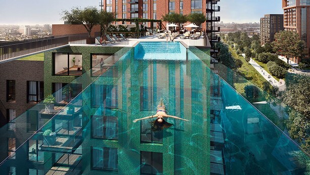 Un edificio moderno con piscina de fondo de cristal, rodeado de vegetación y otros edificios.
