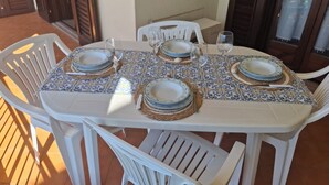 A dining table set with plates, glasses, and cutlery, surrounded by white chairs. - VACATION HOME SUN & BEACH - LEMONS APARTMENT (Capo d'Orlando)