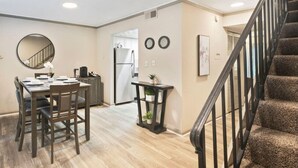 A spacious living area with a dining table, chairs, a staircase, and a kitchen in the background. - King Bed, 5 min walk Truist Park | The Battery (Smyrna)