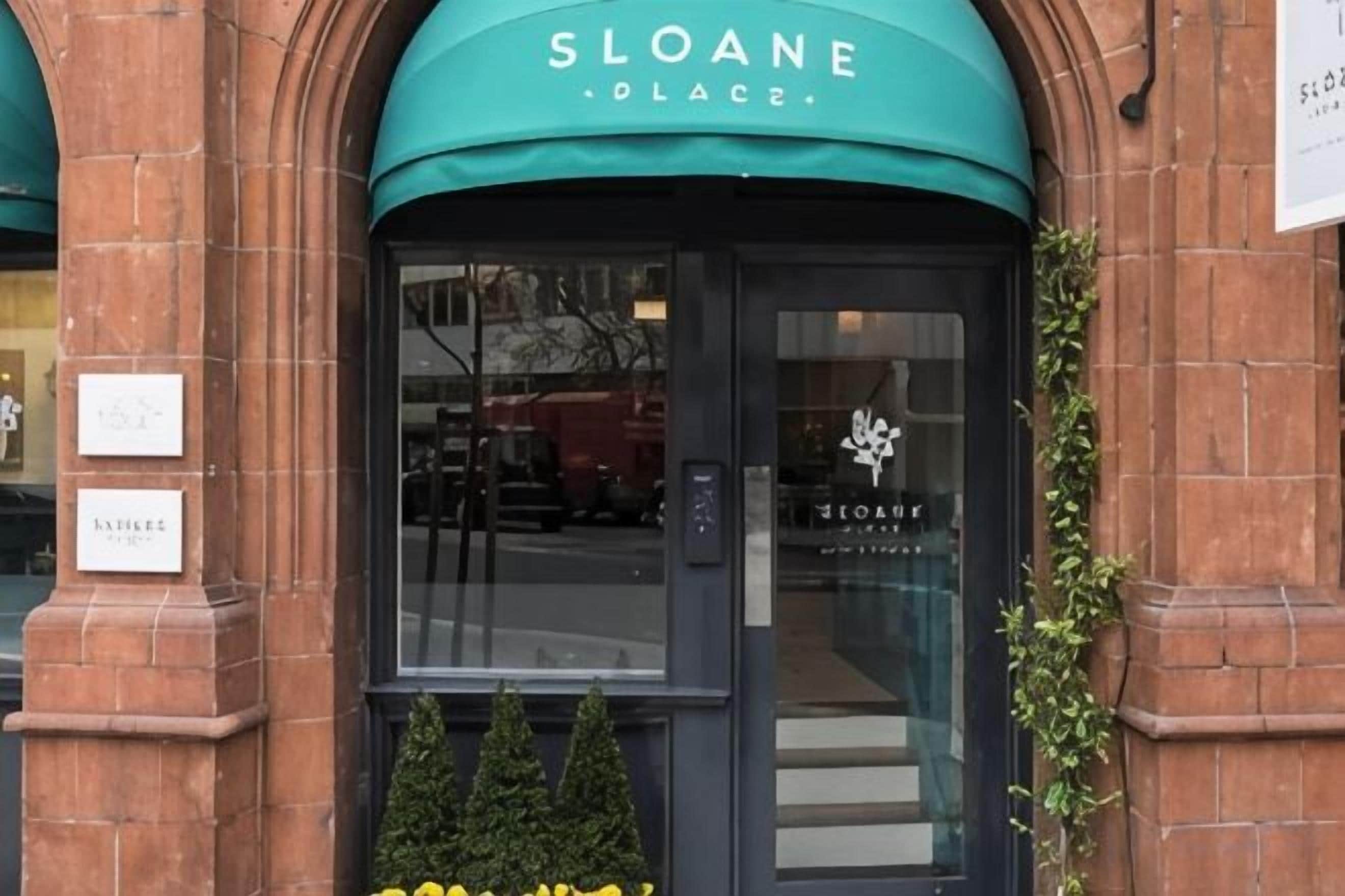A brick building with a green awning labeled 'SLOANE PLACE.'