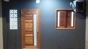 A building with a dark facade, a wooden door, and a window. - Loft Pajuçara (Maceio)