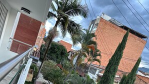 A residential area with a paved walkway, palm trees, and a brick building. - Spacious 3BR in Central Medellín • Home Theater • Near Laureles & Poblado
 (Medellín)