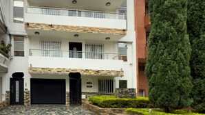 A multi-story residential building with a stone facade, a garage, and a well-maintained garden. - Spacious 3BR in Central Medellín • Home Theater • Near Laureles & Poblado
 (Medellín)
