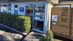 A motel with a welcoming sign, a number 87 sign, and a small potted plant in front. - cherry grove motel (Havelock North)