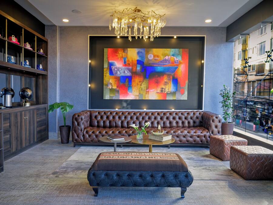 A modern living room with a tufted leather sofa, a coffee table, and a large abstract painting on the wall.
