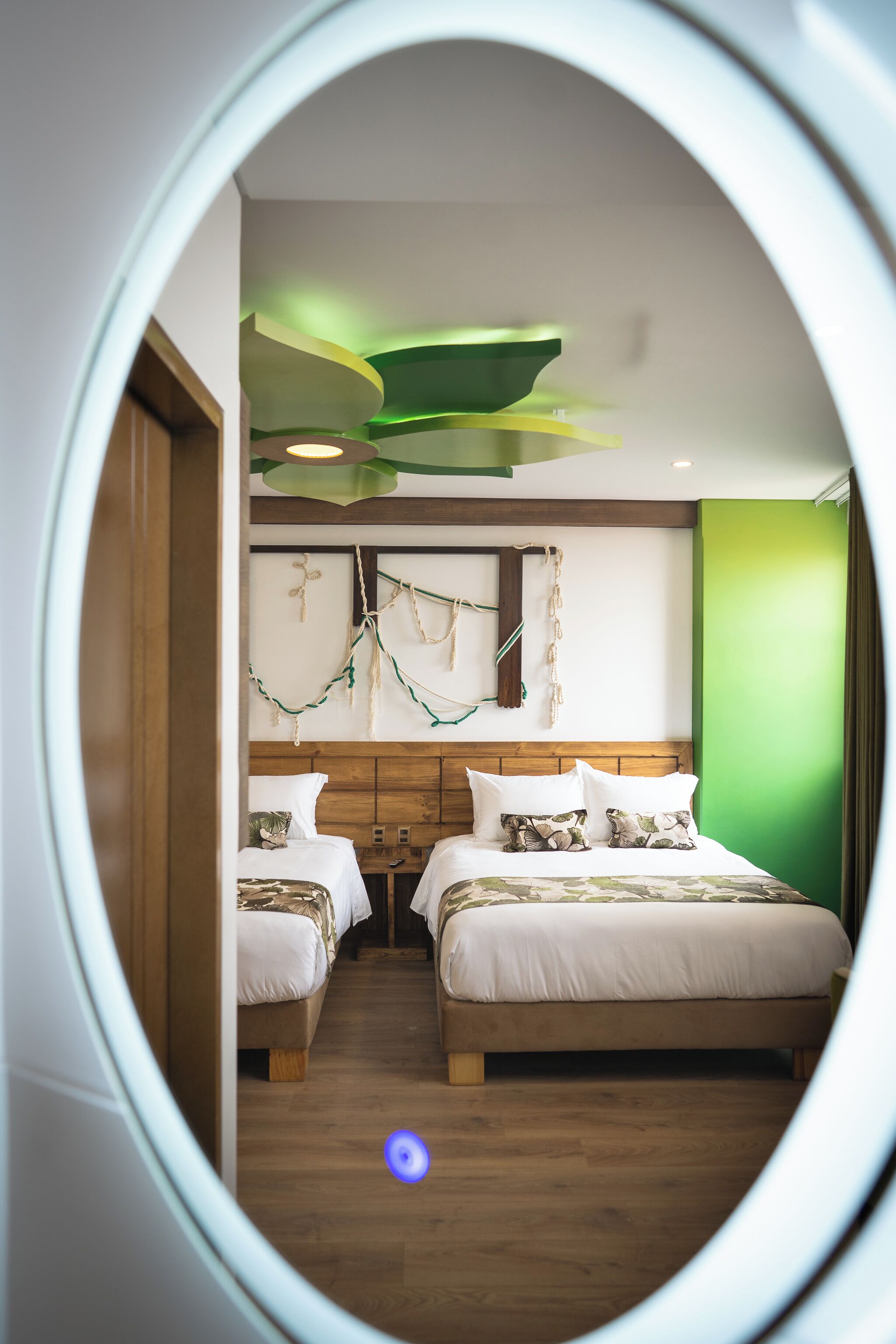 Una habitación con dos camas, cabeceros de madera y una pared verde decorativa.