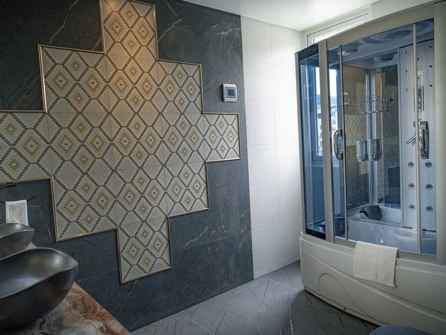 Un baño con un espejo grande, ducha con cerramiento de vidrio y pared revestida de mármol.