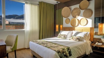 Habitación de hotel con una cama grande, una silla, un escritorio y vistas al exterior.