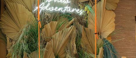 A hanging orange swing chair with a neon sign above it that reads "Pay your dues to new adventures."