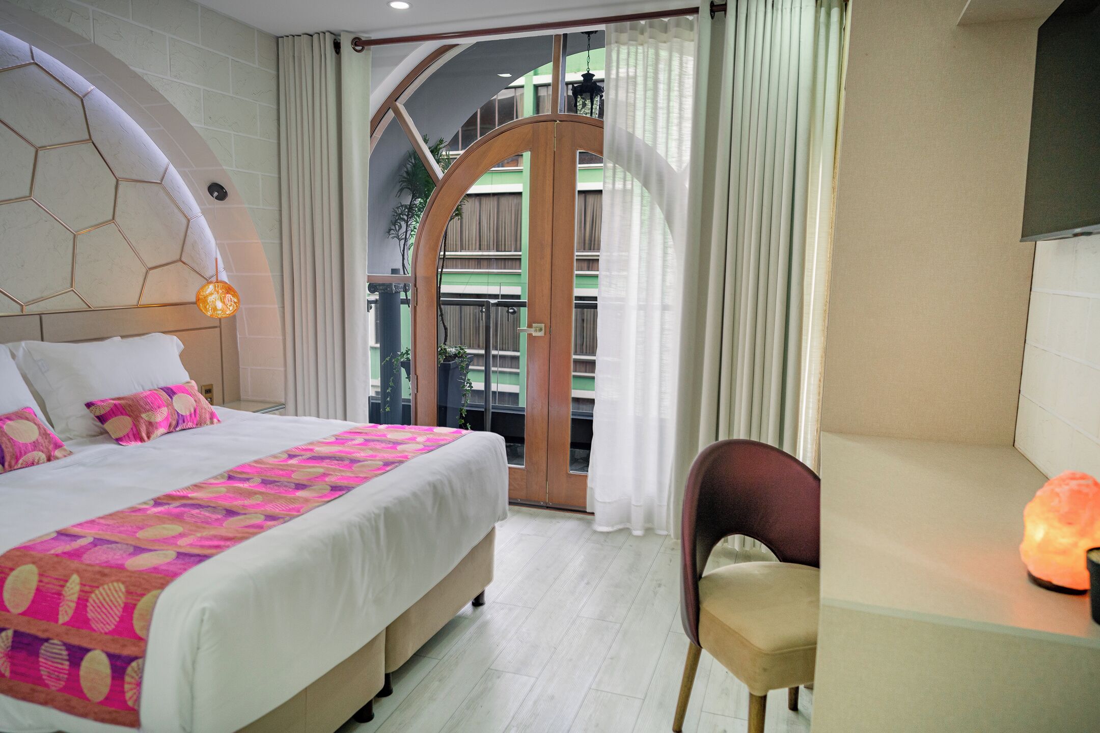 Une chambre à coucher avec un grand lit, une chaise et une table de chevet avec une lampe.