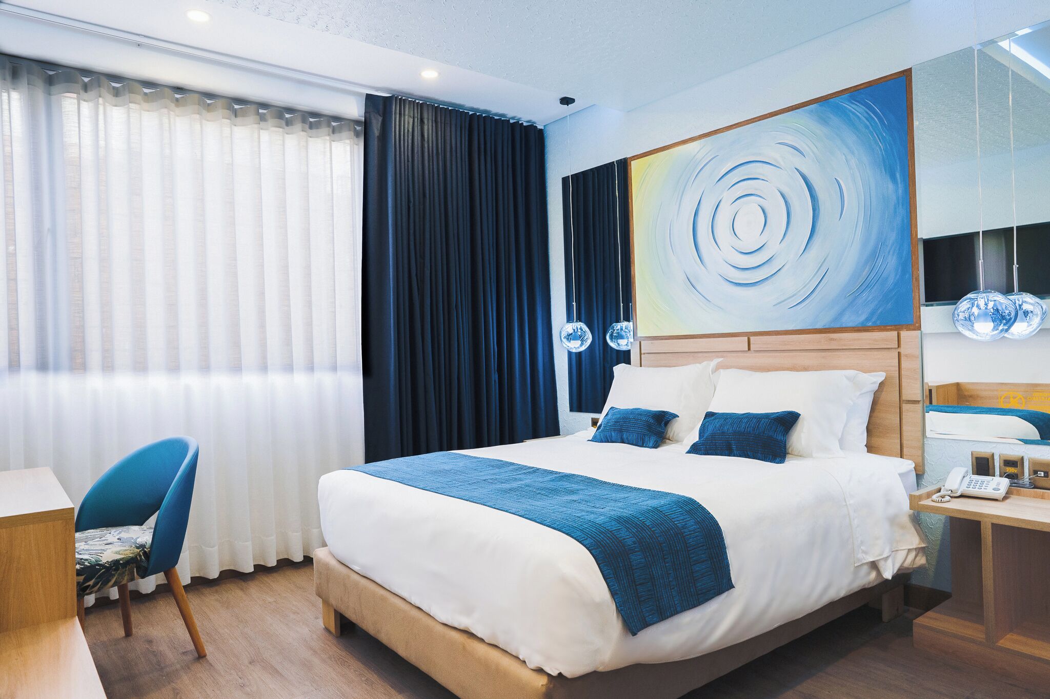 Una camera d'hotel con un letto grande, una scrivania, una sedia e un quadro appeso al muro.