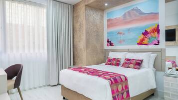 Una habitación de hotel con una cama grande, un escritorio y un cuadro en la pared.