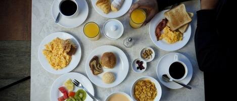 Una mesa con alimentos para el desayuno, como huevos, tostadas y fruta.